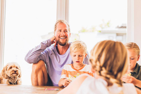 A parent sitting with his children and a dog at a table. 