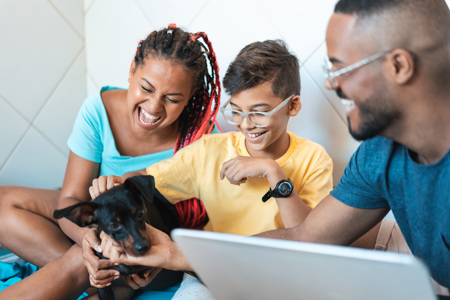 A family sitting down playing with their dog. 
