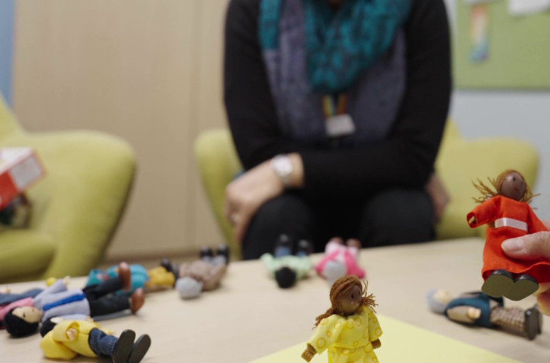 A person picking up toy figurines that are laying on a table 