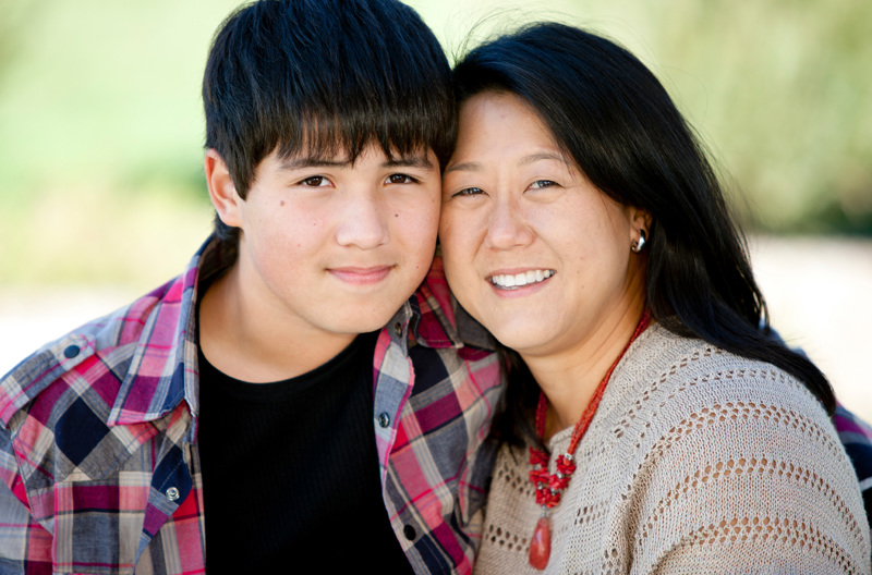A teen with their arm wrapped around their parents shoulder.