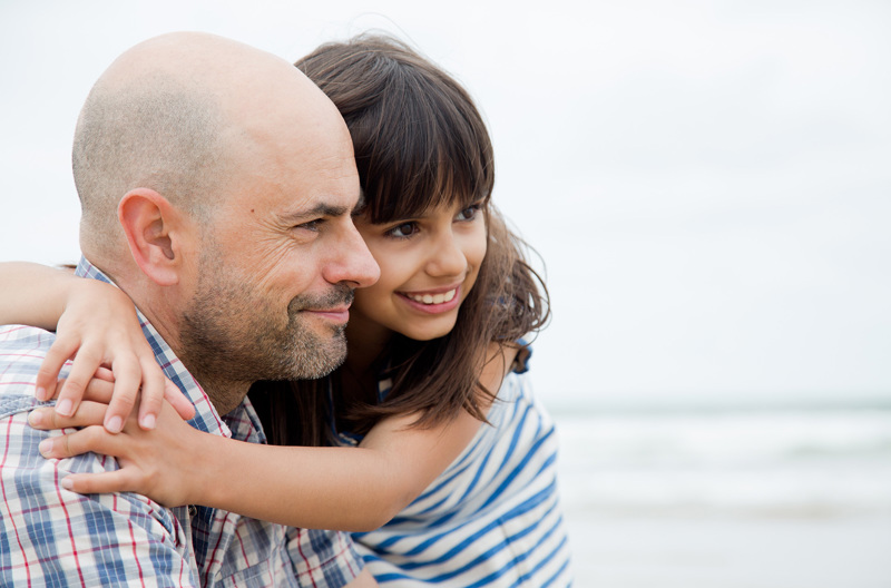 A child hugging her parent while they look off into the distance. 
