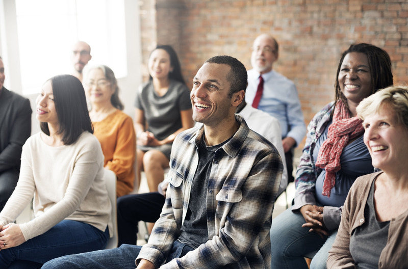 A large classroom full of people smiling while looking off into the distance