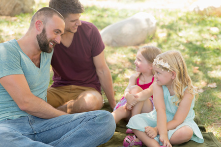 Two parents sitting with their children on grass. 