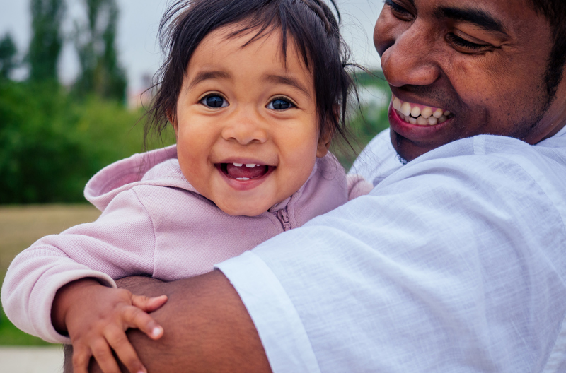 A father smiling while he holds his daughter