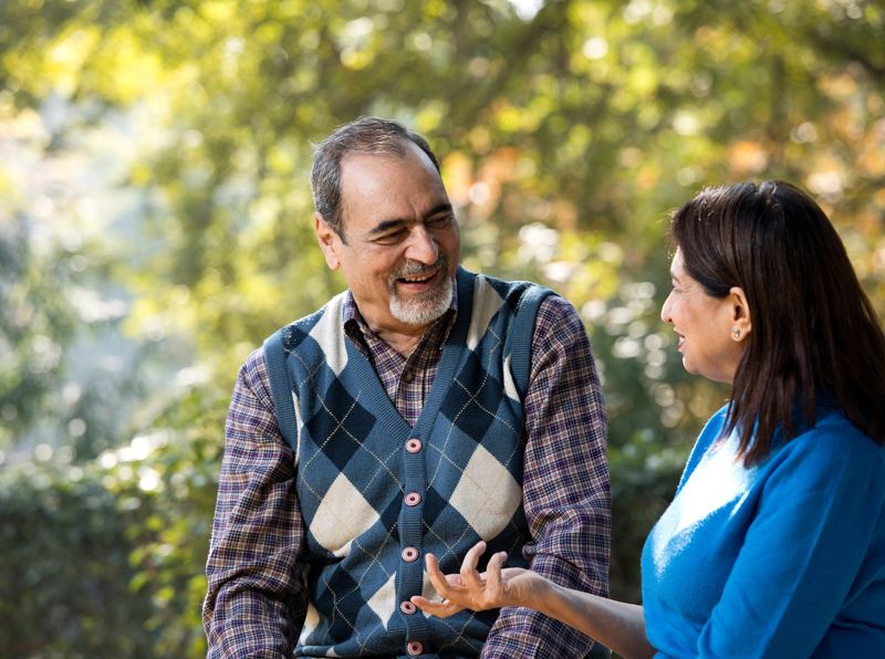 A couple sitting outside smiling while they talk to each other