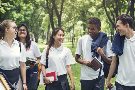 Five teenagers walking next to each other through a park
